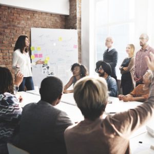 A meeting of professionals with someone raising their hand to speak