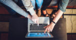 Three people helping each other understand what is on a laptop screen thanks to digital text accessibility
