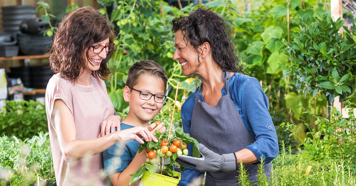Two women and a boy in a garden looking at fresh vegetables and explaining what the term dietitian means