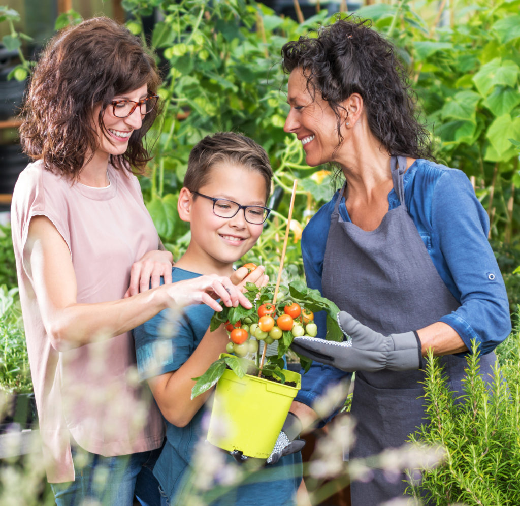 Two women and a boy in a garden looking at fresh vegetables and explaining what the term dietitian means