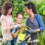 Two women and a boy in a garden looking at fresh vegetables and explaining what the term dietitian means