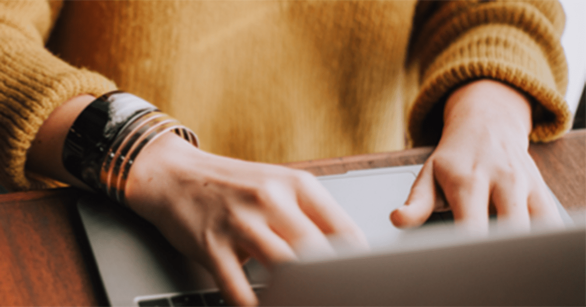 Student in Sweater on Laptop Taking a Online Social Work Course