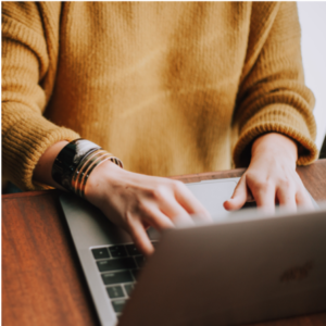 Student in Sweater on Laptop Taking a Online Social Work Course