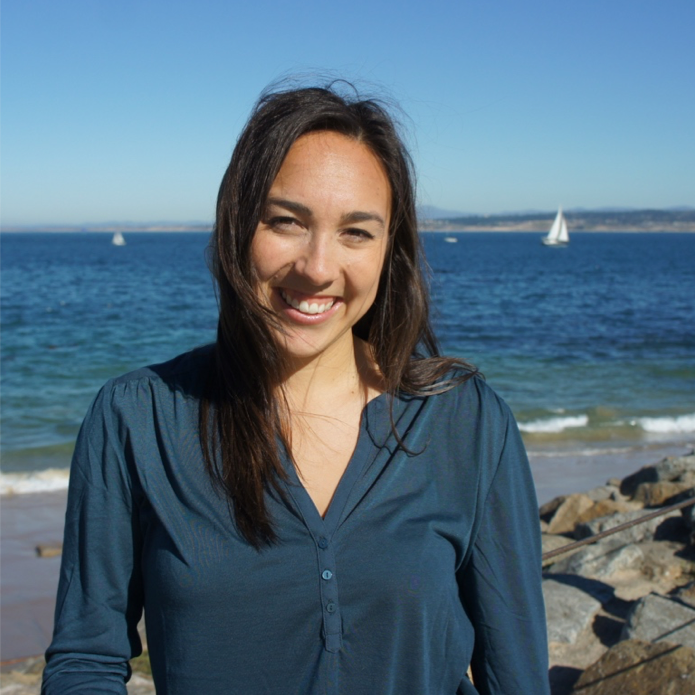 Monica Huelga, who completed her Master of Public Health practicum presentation on environmental health literacy, stands in front of the Pacific ocean with a sailboat in the background