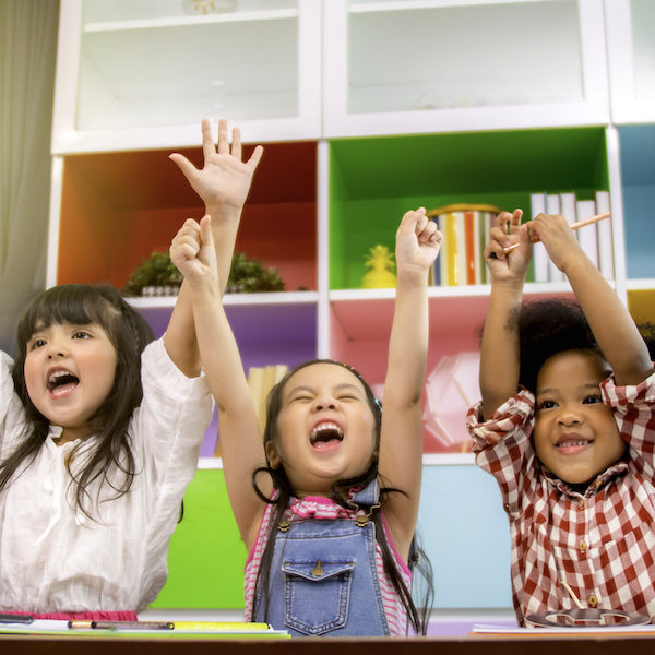 Three girl students throw their hands up in excitement because their teacher used school data analysis