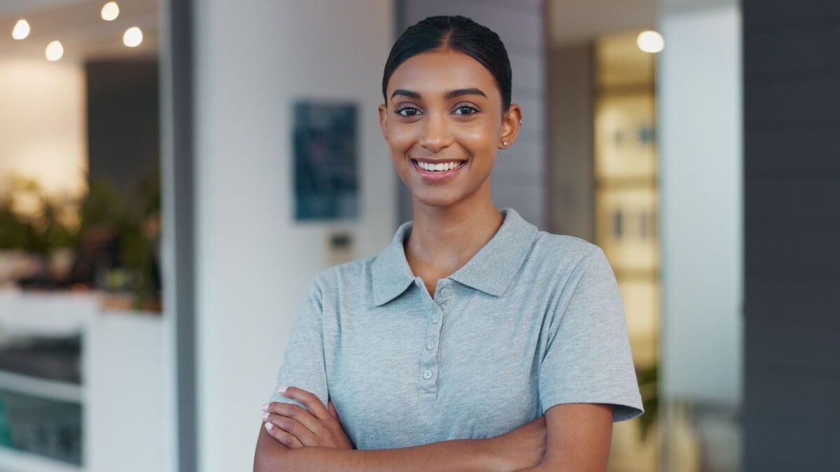 Portrait, woman and confidence as physiotherapist in gym, rehabilitation clinic or wellness practice. Female person, pride and arms crossed with smile, personal trainer or coach for physio exercise