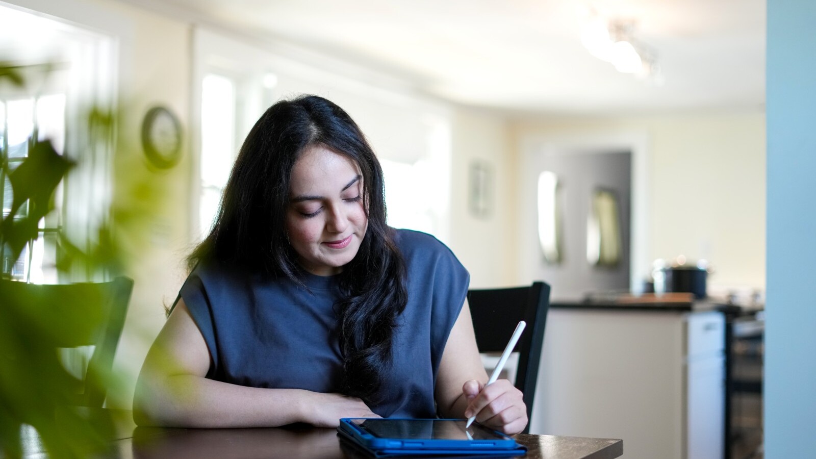 Student sitting at a table using a tablet with a stylus
