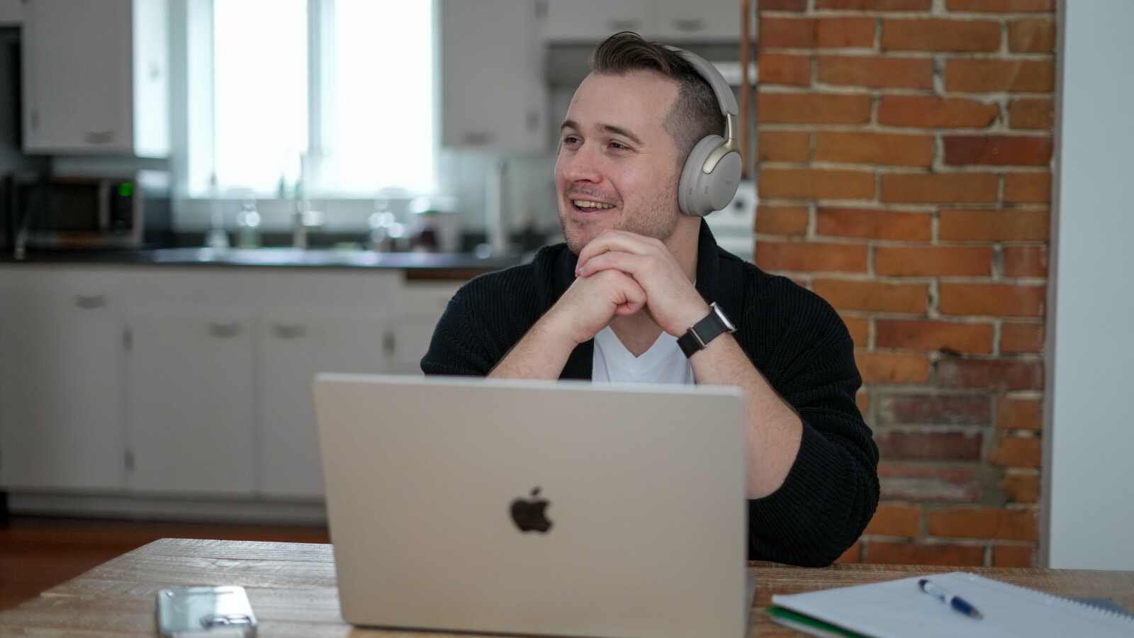 Student with headphones sitting at a table with a laptop notebook and phone