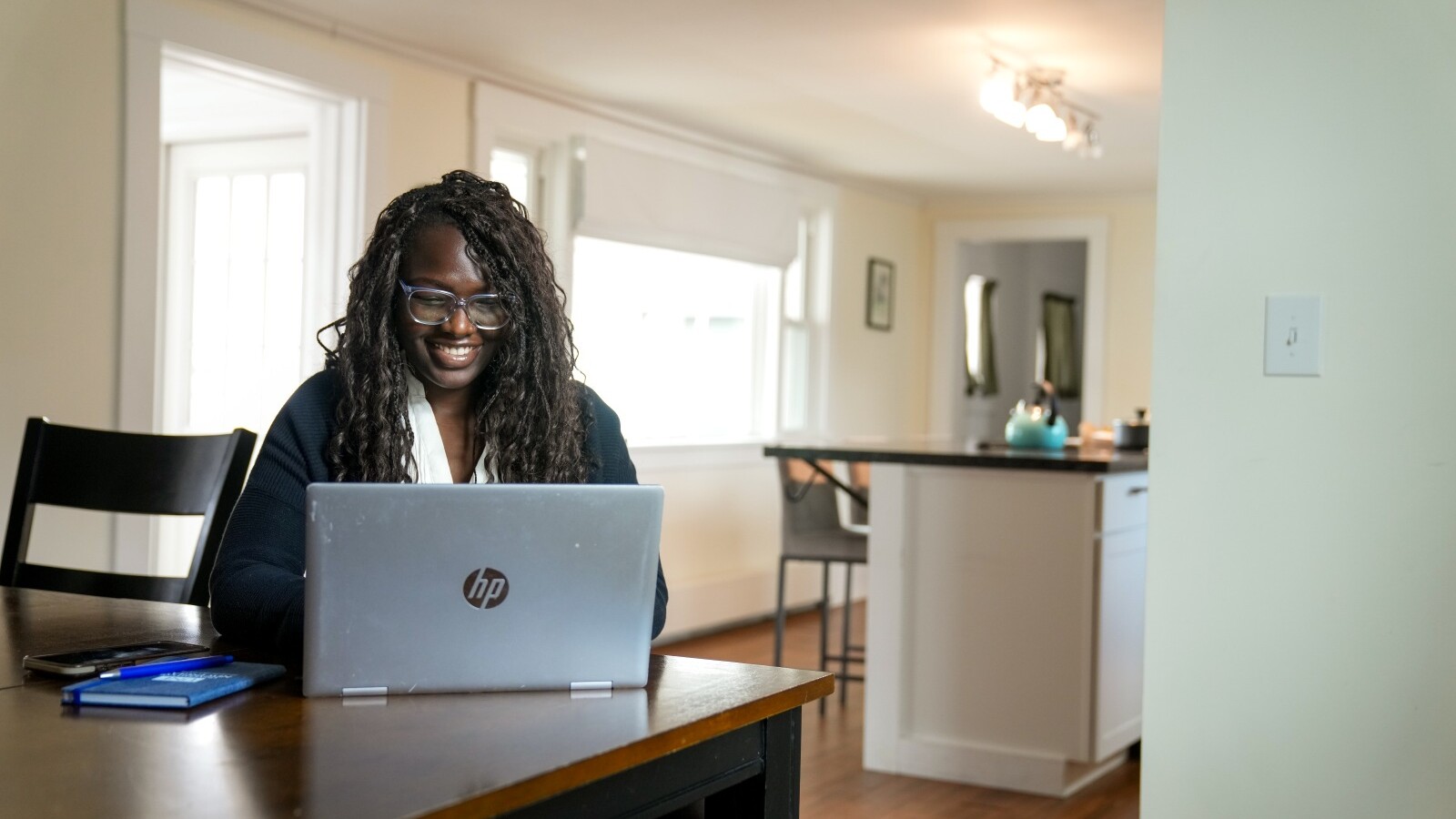 Student smiling while working on a laptop at a table