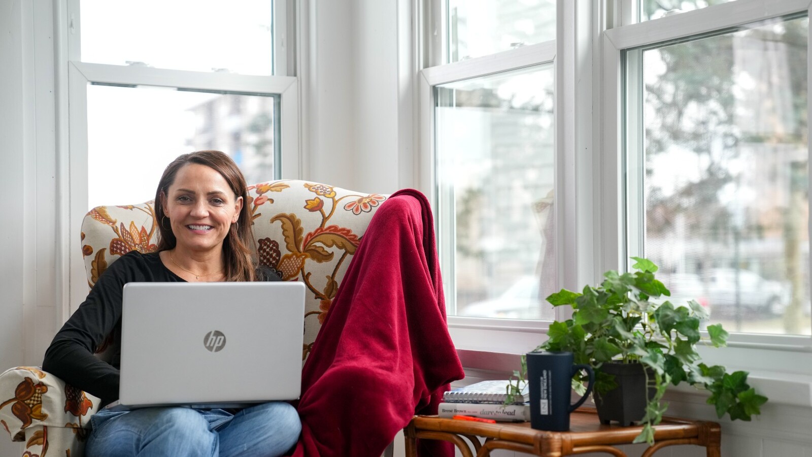 Student sitting in a chair with a red blanket while using a laptop