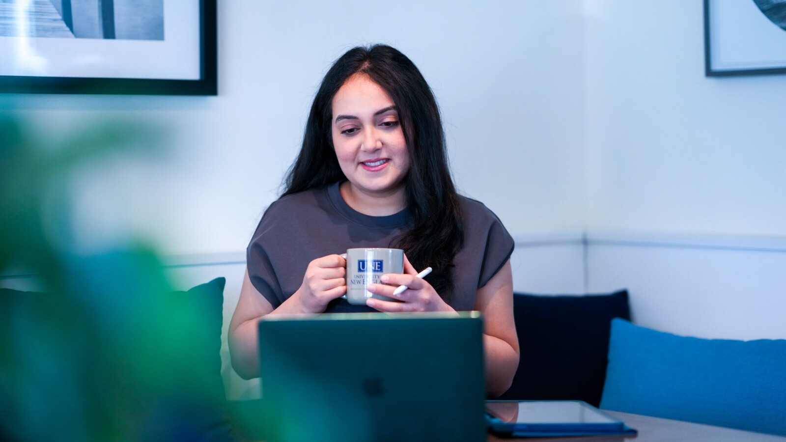Student holding a mug looking at a laptop on a table