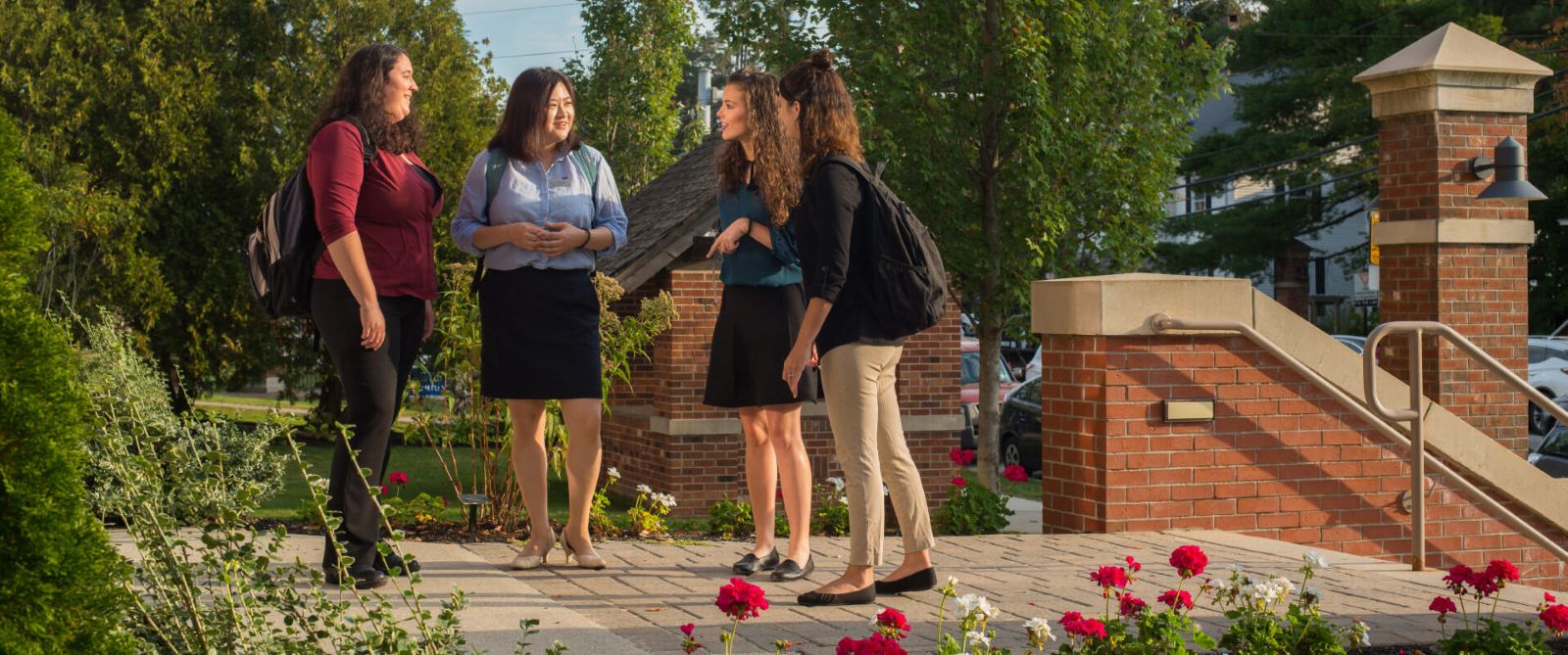 Students speaking on a patio with flowers in the floreground