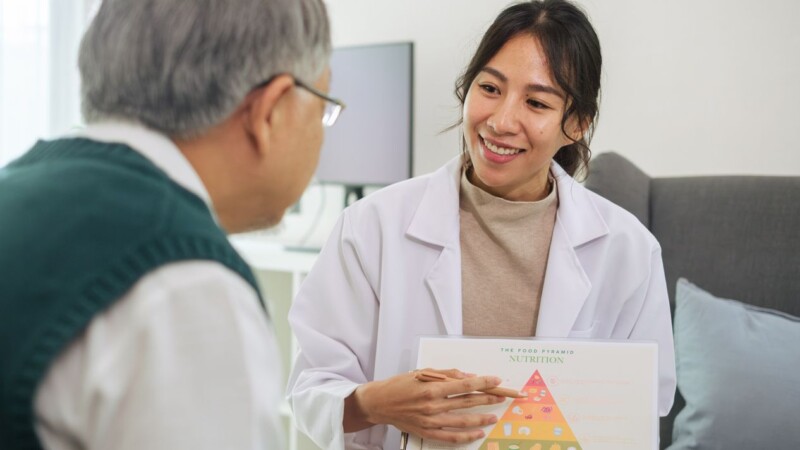 Doctor Explaining Healthy Eating and Food Pyramid to Senior Patient During Nutrition Counseling