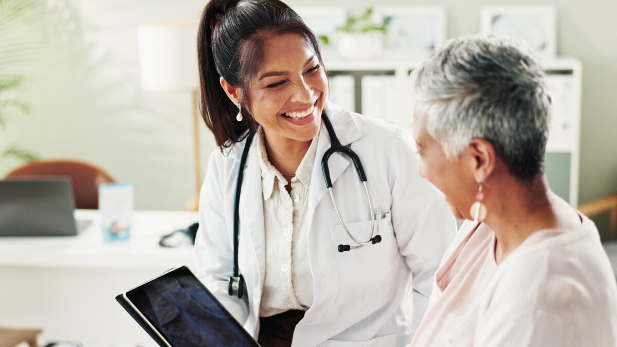 Mature woman, doctor and tablet for xray, support or conversation with cardiology checkup in office. Female person, medical professional and diagnosis talk for senior patient at clinic appointment