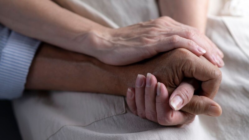 Close up image of senior couple holding hands together.