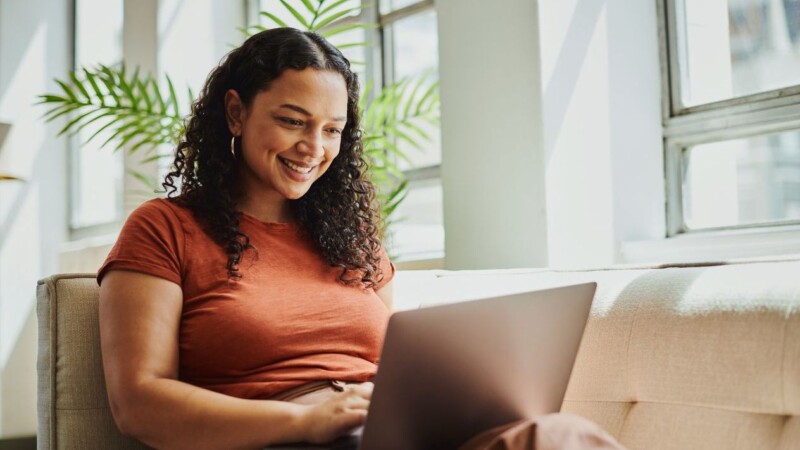 Shot of a young woman sitting with her laptop, smiling