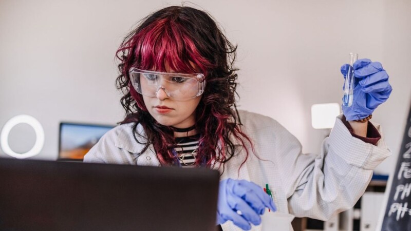 Female university student wearing lab coat while working on project in lab on scientific research