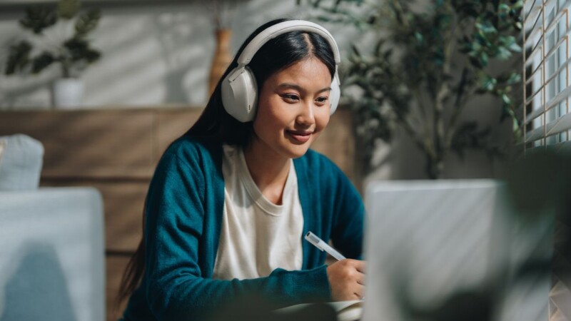 Woman enjoying her online class, attentively taking notes as she stays engaged and focused. With a sense of curiosity and dedication, she embraces the opportunity to learn from home and improve her knowledge