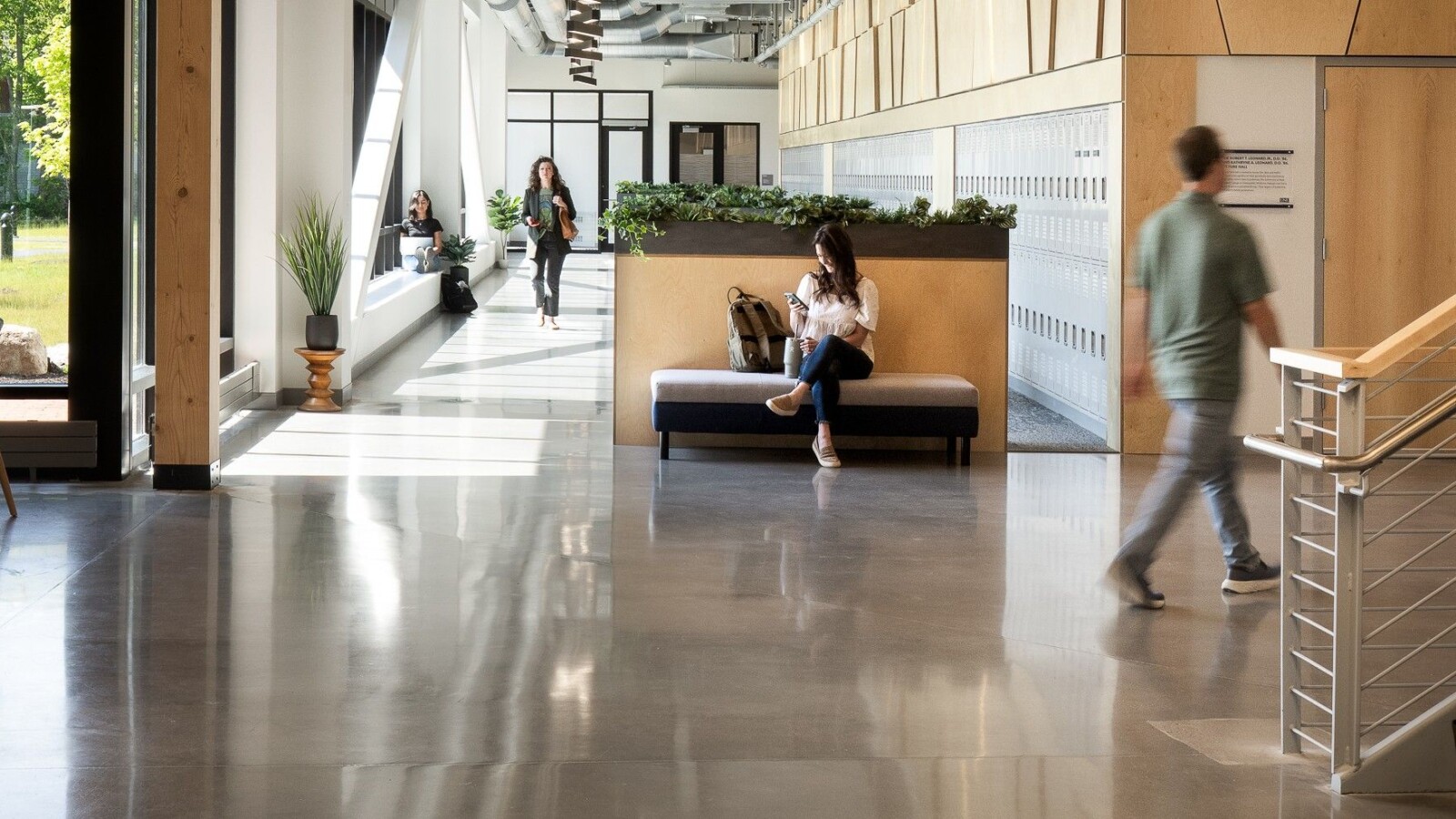 People sitting and walking in a spacious hallway in the UNE Health Sciences Building
