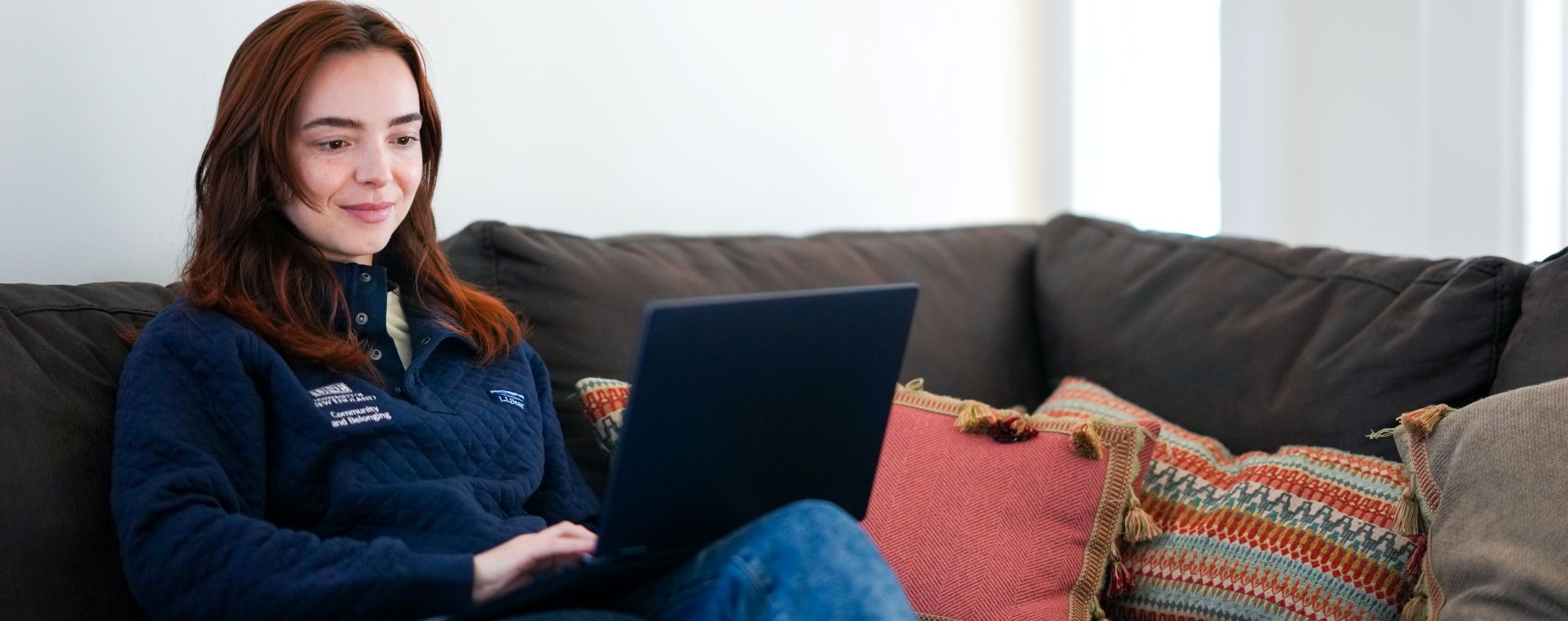 Student sitting on a couch working on a laptop