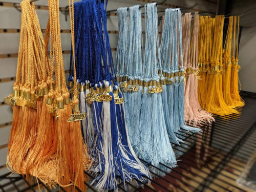 At UNE the Master’s of Social Work is designated by a citron tassel, the Master of Education is designated with a light blue tassel, Master of Public Health is designated with a salmon tassel, and the Master of Applied Nutrition and Health Informatics programs are designated with a science gold tassel. The blue and white tassel pictured is for the bachelor’s degrees awarded by the university.